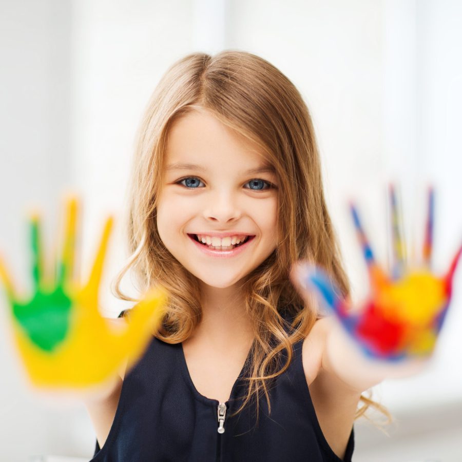 education, school, art and painitng concept - smiling little student girl showing painted hands at school